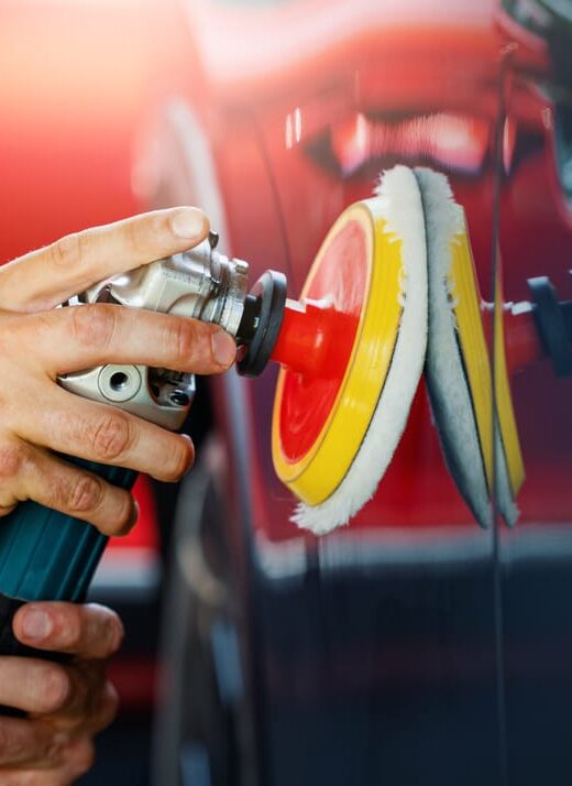 car body repair and detailing workshop. man polishing vehicle paint.