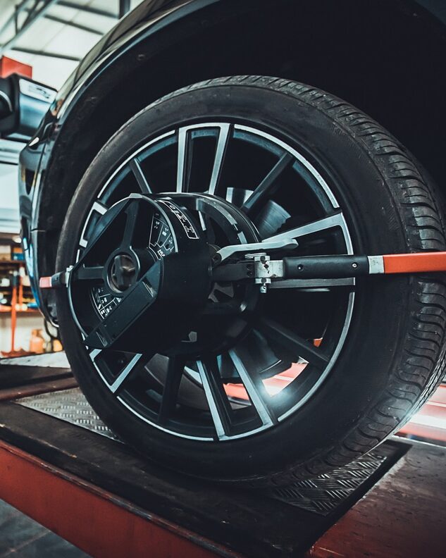 One man, mechanic in auto repair shop, wheel alignment equipment on a car wheel in a repair station.