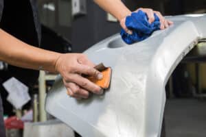 Closeup of mechanic's hand sanding bumper