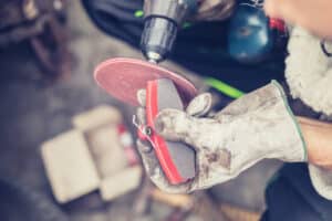 DIY - man repairing disc brake at vintage car, replacing brake pads at parking lot, sanding brake pads using multi tool with sand extender, real people