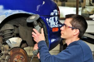 Man grinding a car panel with a drill.