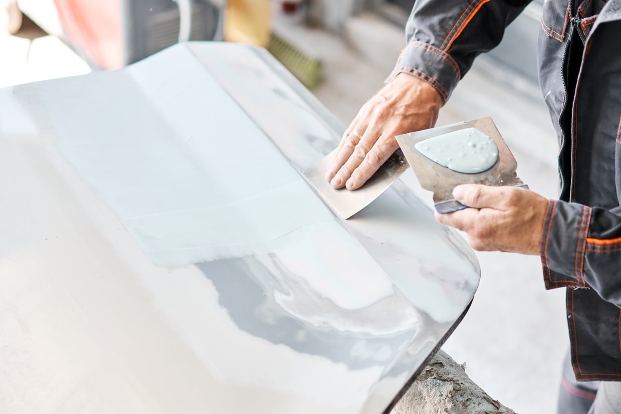 Repairing car body, Application putty close up. The mechanic repair the car. Work after the accident by working sanding primer before painting