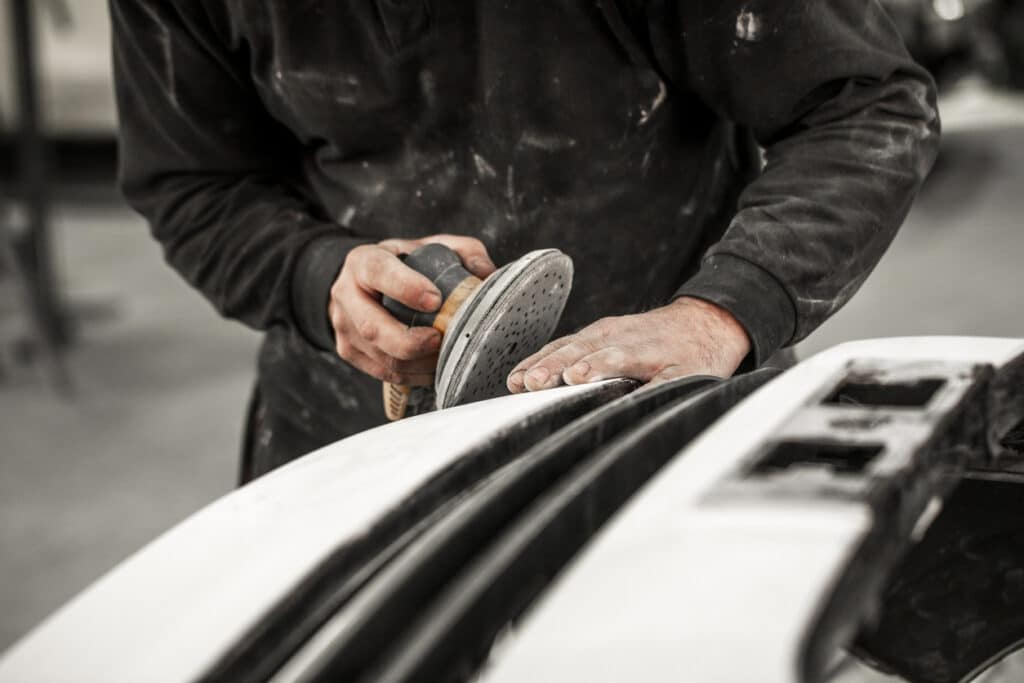 Cropped photo of a mechanic using a disc sander on car