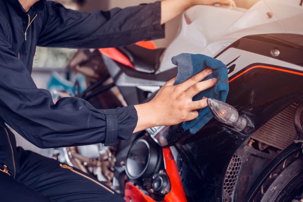Cropped image of a man cleaning a motorcycle with a cloth