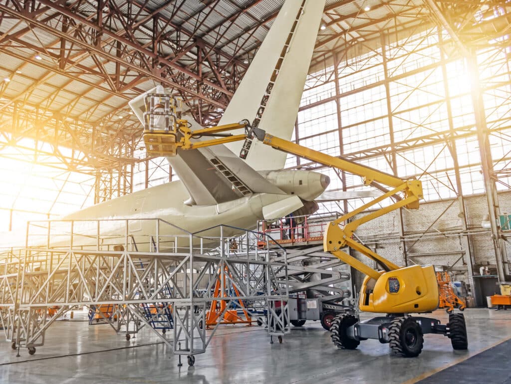 Aeroplane being painted in a hangar by professionals.