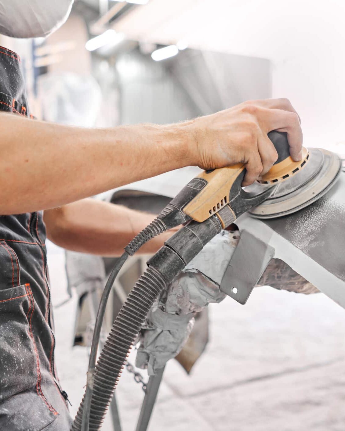 Mechanic using grinding tool to sand car elements down.