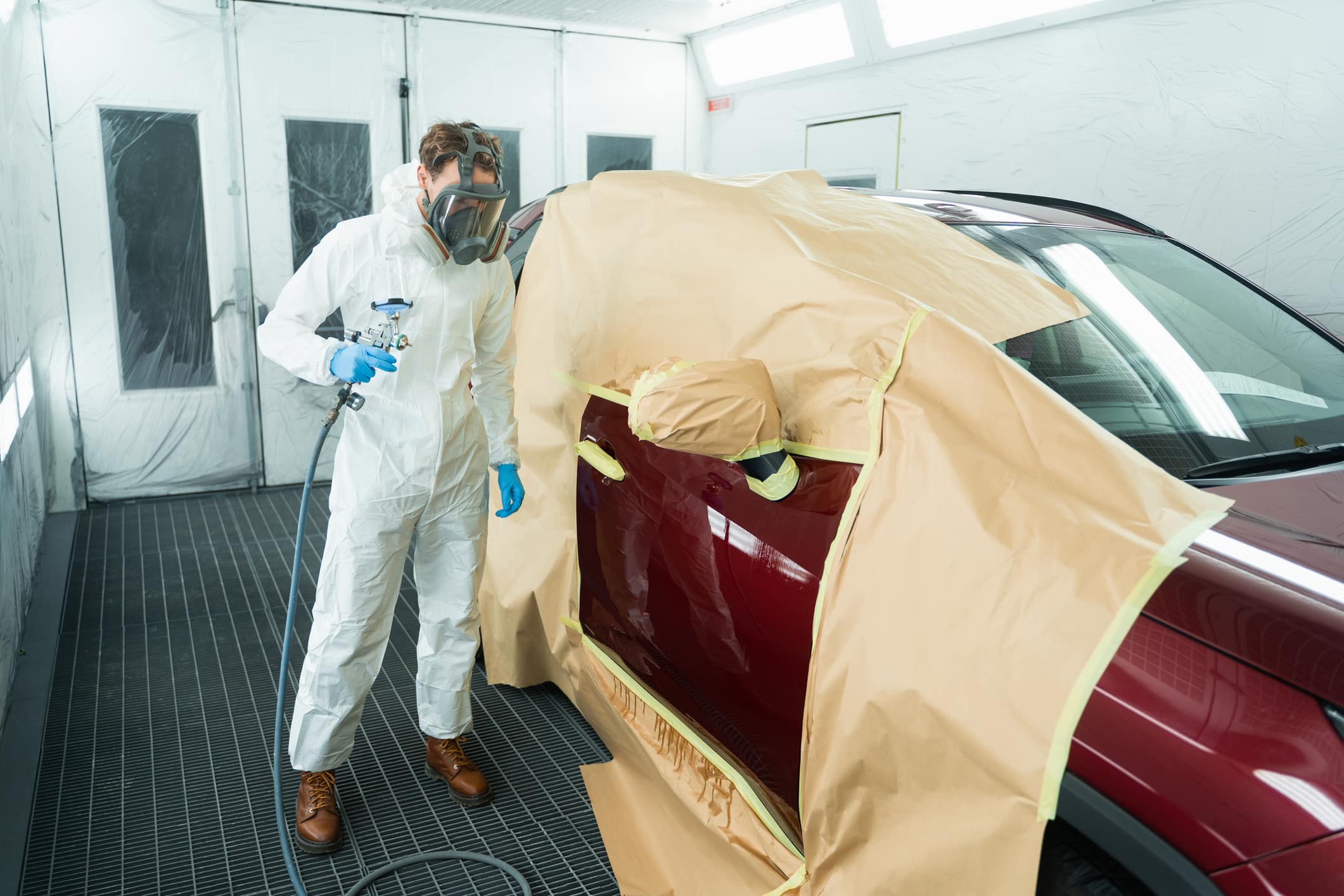 Auto painter with spray gun in car painting booth